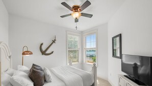 A bedroom with a bed, a ceiling fan, a TV, and windows with blinds. - Kiser Island (Terrell)