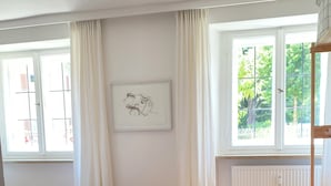 Un dormitorio con cama, un radiador, una ventana con cortinas e imagen enmarcada en la pared.