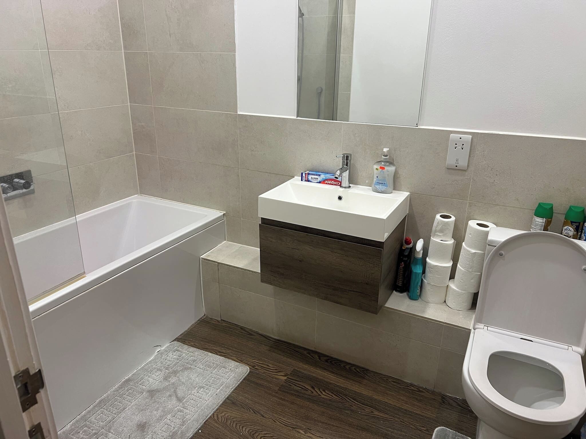 Ein Badezimmer mit einer Badewanne, einem Waschbecken mit Pflegeprodukten, einer Toilette und einem Spiegel.