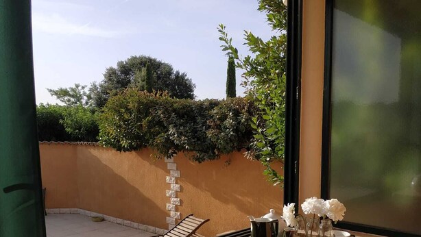 Un balcón con una mesa, sillas y vistas a un jardín.