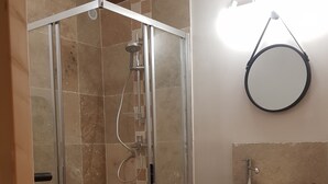Une salle de bain moderne avec une douche à parois de verre, un meuble-lavabo en bois doté d’un vasque et un miroir au-dessus du lavabo.