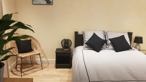 Une chambre à coucher comprenant un lit, une chaise, une table de chevet, une lampe et un tableau accroché au mur.