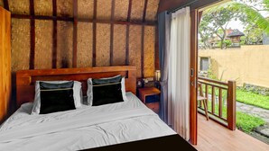 A room with a bed, wooden headboard, and a view of a garden through an open door.