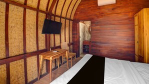 A room with a bed, a wooden desk, a chair, a television, and a wardrobe.