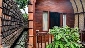 A wooden building with a balcony, a stone wall, and a green plant.