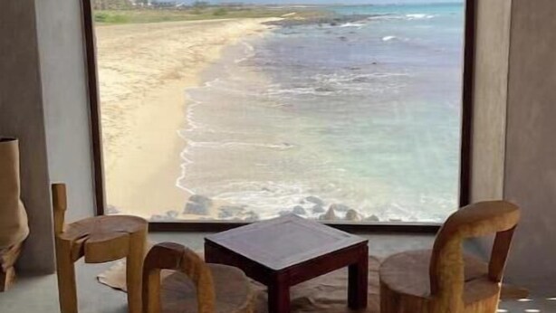 A room with a large window overlooking a beach, two wooden chairs, a small table, and a fur rug on the floor. - Terrace with sea views! #Amazing sea views! (Santa Maria)