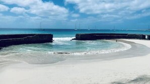 A beach with calm waters, a clear sky, and distant sailboats. - Terrace with sea views! #Amazing sea views! (Santa Maria)
