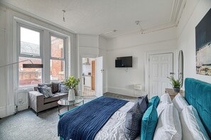 A modern bedroom with a bed, sofa, TV, and a view of the outside. - Glendale House by Guestz (Lytham-St-Annes)
