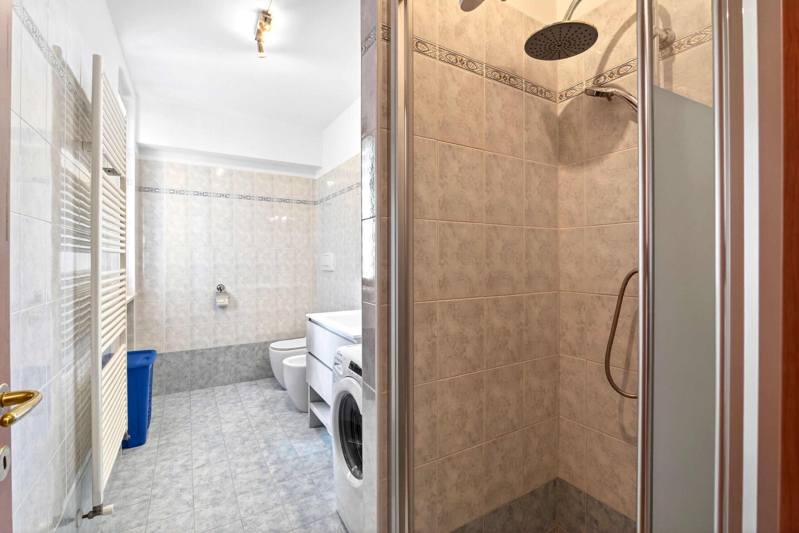 A bathroom with a shower, toilet, and washing machine.