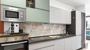Una cocina moderna con microondas, horno y cafetera integrada.