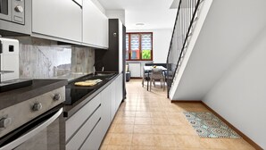 Una cocina moderna con armarios blancos, encimera negra y suelo de baldosas.