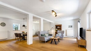 Un amplio salón con sofá, mesa de centro y mueble para televisión.