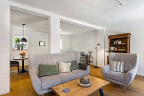 A living room with a sofa, armchair, coffee table, and a bookshelf.