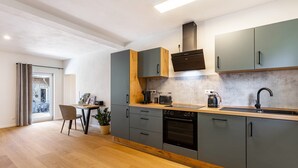 Una cocina moderna con armarios grises, encimera de madera, horno empotrado y ventana con vistas a un paisaje urbano.