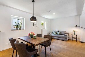 A modern living space with a dining area, sofa, and a floor lamp. - Holiday Home 'Lilla Huset' with Private Terrace and Wi-Fi (Arnsberg)