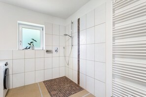Ein Badezimmer mit Dusche, Fenster und Handtuchhalter.