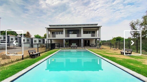 A modern two-story building with a swimming pool in front. - 2 minutes to the mall, restaurants gym, shops all amenities 2 minutes away. (Sandton)
