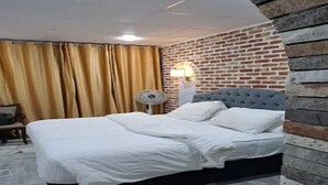 A hotel room with a bed, curtains, a lamp, and a brick wall. - Hotel Hayatt Sukkur (Sukkur)