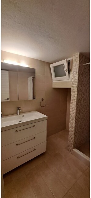 Een badkamer met een wastafel, spiegel en raam.