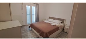 Een slaapkamer met een bed, nachtkastjes, een kledingkast en een raam met gordijnen.