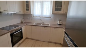 A kitchen with a stove, oven, sink, and cabinets. - Central Paroikia Apartment - 10min walk to Port and Beach! (Paros)