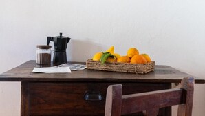 Et træbord med en kaffemaskine, en kurv med appelsiner og et glasdisplay.