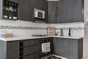 Una cocina con armarios de madera oscura, microondas, estufa a gas y salpicadero de azulejos.