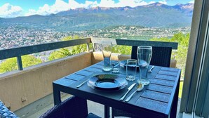 A table set outdoors with a mountain view, a glass of water, and a candle. - Bella-Lugano vacation apartment (Aldesago)