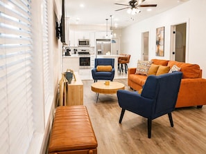 A modern living room with a sofa, armchair, bench, and coffee table. - Fire Pit Home by Mercedes-Benz Stadium (Atlanta)