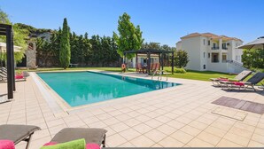 A swimming pool with lounge chairs, a gazebo, and a building with a tiled roof. - Villa Amarandes With Private Pool (Rhodes)