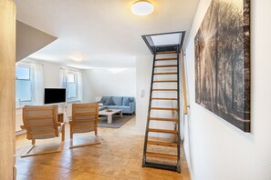 A modern living room with a wooden ladder, a sofa, and a painting on the wall. - Holiday Apartment 'Glück in Dornum' with Wi-Fi (Dornum)