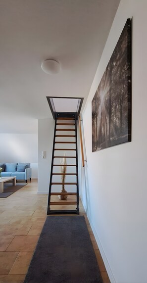 Ein modernes Interieur mit Treppe, einem Wohnzimmer inklusive Sofa und einem großen, gerahmten Bild an der Wand.