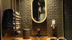 Een badkamer met een ronde spiegel, een wastafel van glas, handdoeken en een handdoekhouder.