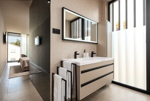 Un baño moderno con un espejo grande, dos lavamanos y un perchero para toallas.