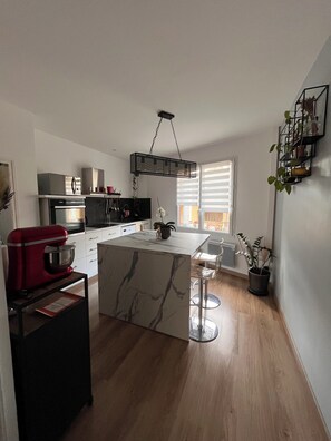 A modern kitchen with a marble island, stainless steel appliances, and a hanging light fixture. - Between lake and sea (Clermont-l'Hérault)