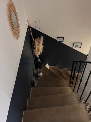 A staircase with a black wall and a white wall, a mirror, and a framed picture on the wall. - Between lake and sea (Clermont-l'Hérault)