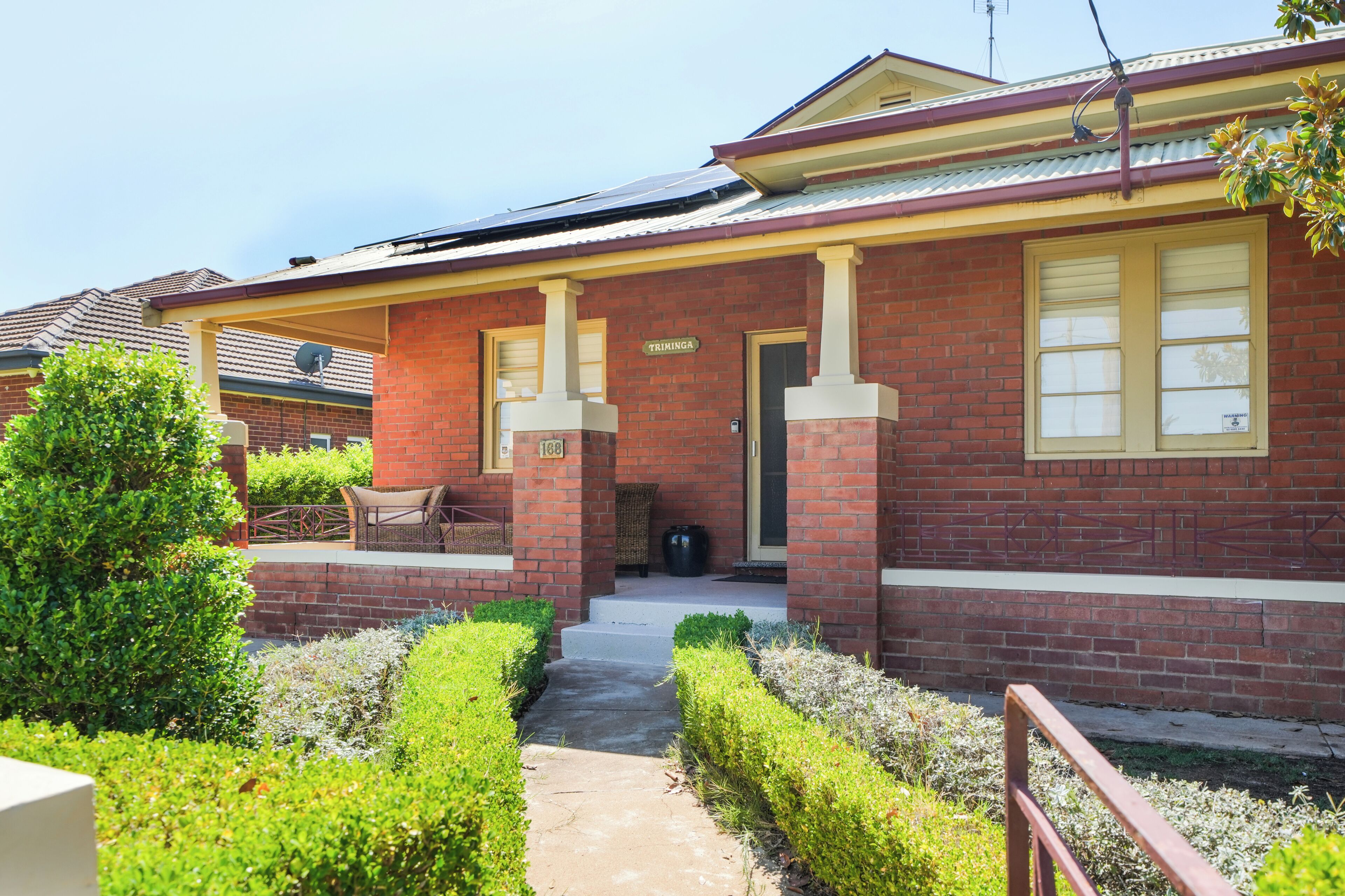 A brick house with a front porch, a mailbox, and a well-maintained garden.