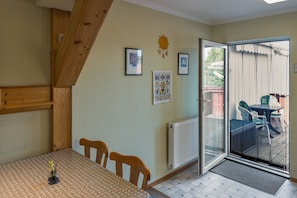 A dining area with a table and chairs, a radiator, and a view through a glass door to an outdoor patio.