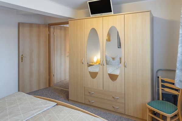 Ein Schlafzimmer mit Kleiderschrank, einem Bett, einem Sessel und einem Fernseher.