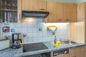 Eine moderne Küche mit Einbauherd, Kaffeemaschine und Spüle.