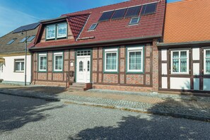 A traditional brick building with a sloped roof, multiple windows, and a visible entrance.