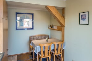 Ein Essbereich mit Tisch und Stühlen, ein Fenster mit Aussicht und eine Holztreppe.