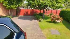 A paved driveway leading to a red gate, surrounded by greenery and a hedge. - Apartment 'Für 2 Personen 45 M²' with Private Terrace and Wi-Fi (Bad Wilsnack)