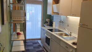 A compact kitchen with a built-in oven, a sink, and a coffee maker. - Apartment 'Für 2 Personen 45 M²' with Private Terrace and Wi-Fi (Bad Wilsnack)
