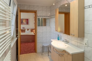 Een moderne badkamer met een wit wastafelmeubel, een spiegel en een douche.