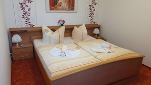 A neatly made bed with towels and pillows, a bedside lamp, and a framed picture on the wall. - Apartment 'Für 2 Personen 45 M²' with Private Terrace and Wi-Fi (Bad Wilsnack)