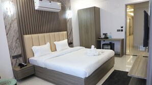Habitació d'hotel moderna amb un llit gran, una taula de nit amb un telèfon, una taula petita amb una cadira i un armari.
