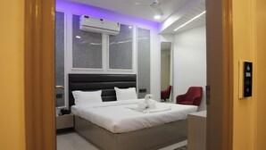 Habitació d'hotel moderna amb un llit gran, una taula de nit, una cadira vermella i un aparell d'aire condicionat.