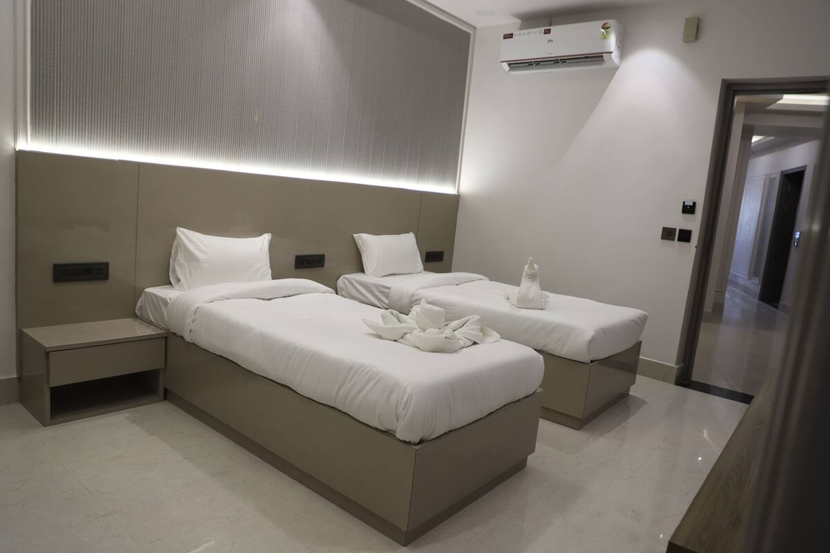 Una habitación de hotel moderna con dos camas, una mesita de noche, un aire acondicionado de pared y un espejo.