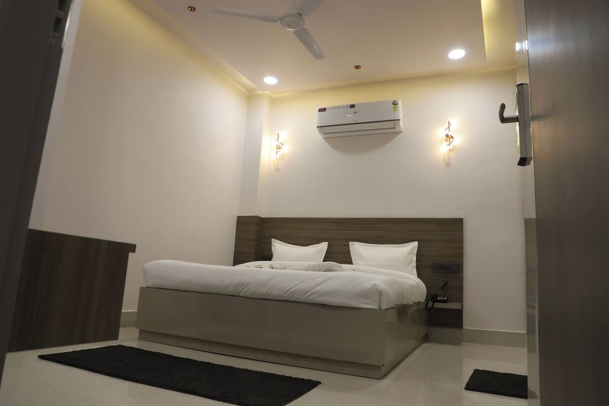 Un dormitorio moderno con cama, mesita de noche, aire acondicionado de pared, ventilador de techo e iluminación empotrada.